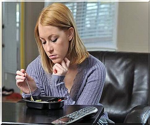 Lonely woman sitting at the table eating