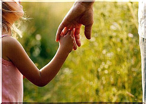 A girl holds her father's hand