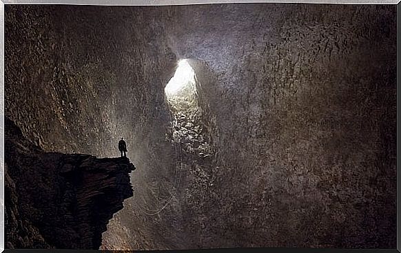 Man standing in a deep cave, because reaching your bottom can sometimes feel like this