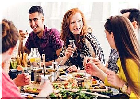 A group of people are sitting at the table eating and talking